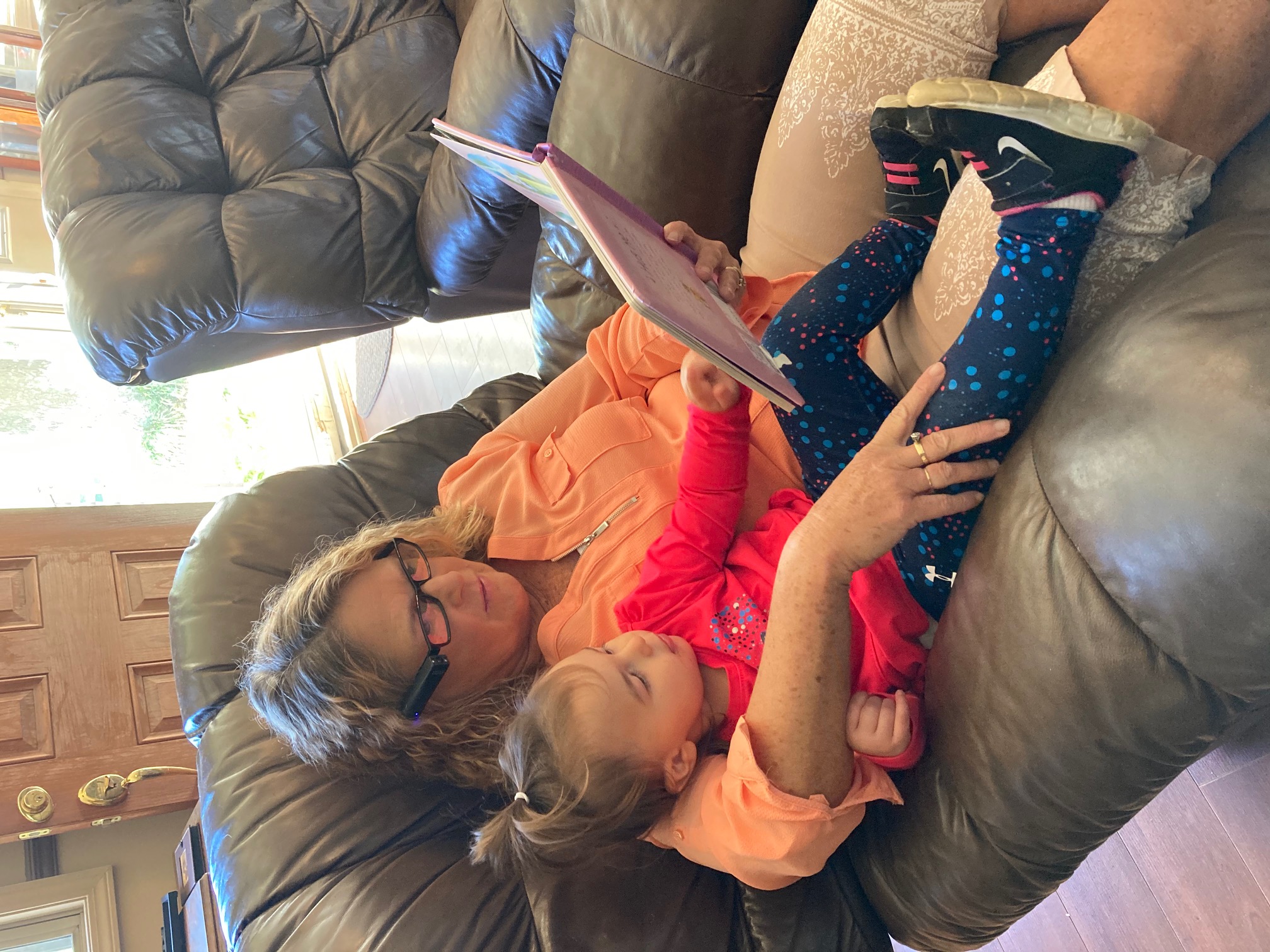 Front view of Teresa reading book to grand daughter