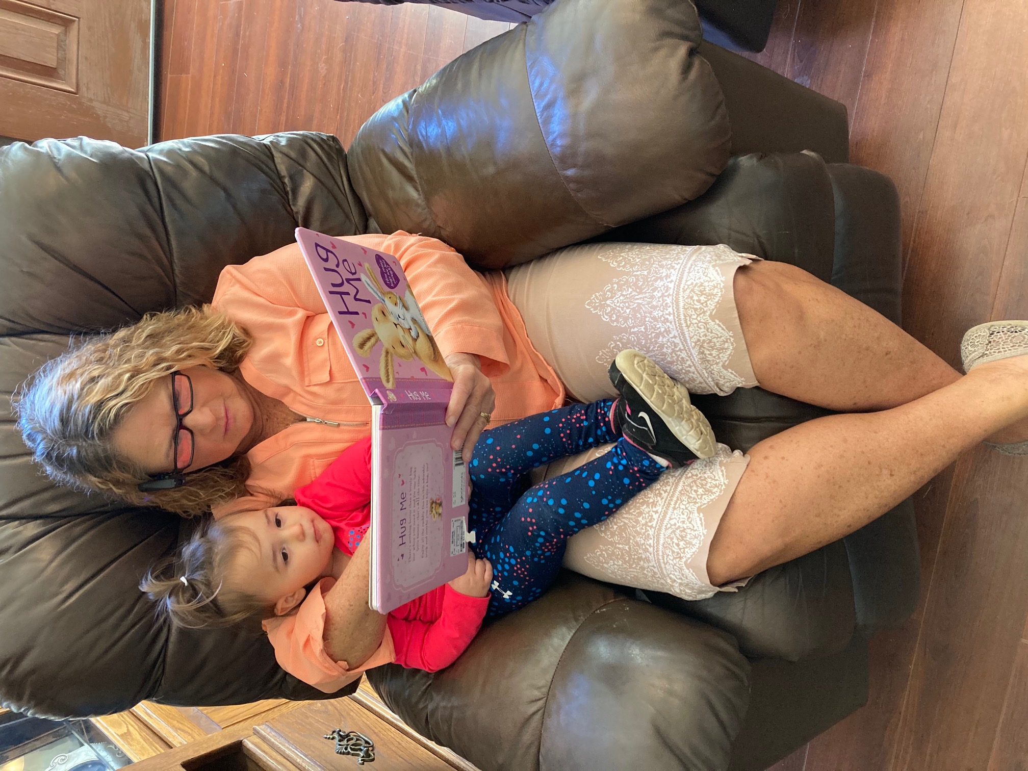 Side view of Teresa reading book to grand daughter